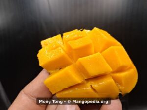 Mong Tong mango cut cheek showing dark orange flesh - Mong Tong mango