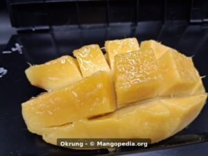 Okrung mango cut cheek closeup showing smooth juicy yellow flesh - Okrung mango